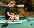 wildlife photographer in stable kayak looking through telescopic lens 120