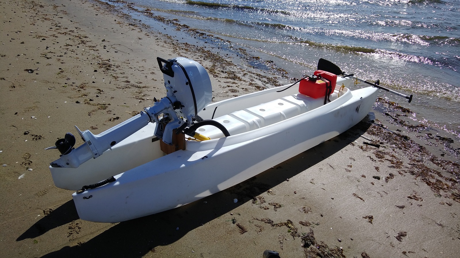 W720 Kayak Skiff with 6 HP Tohatsu outboard motor on the beach, ready to launch